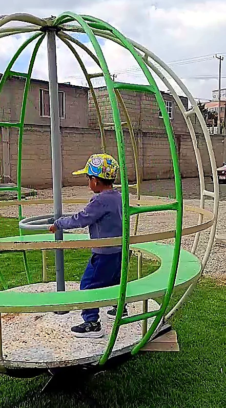 Niño jugando en el carrusel giratorio del jardín